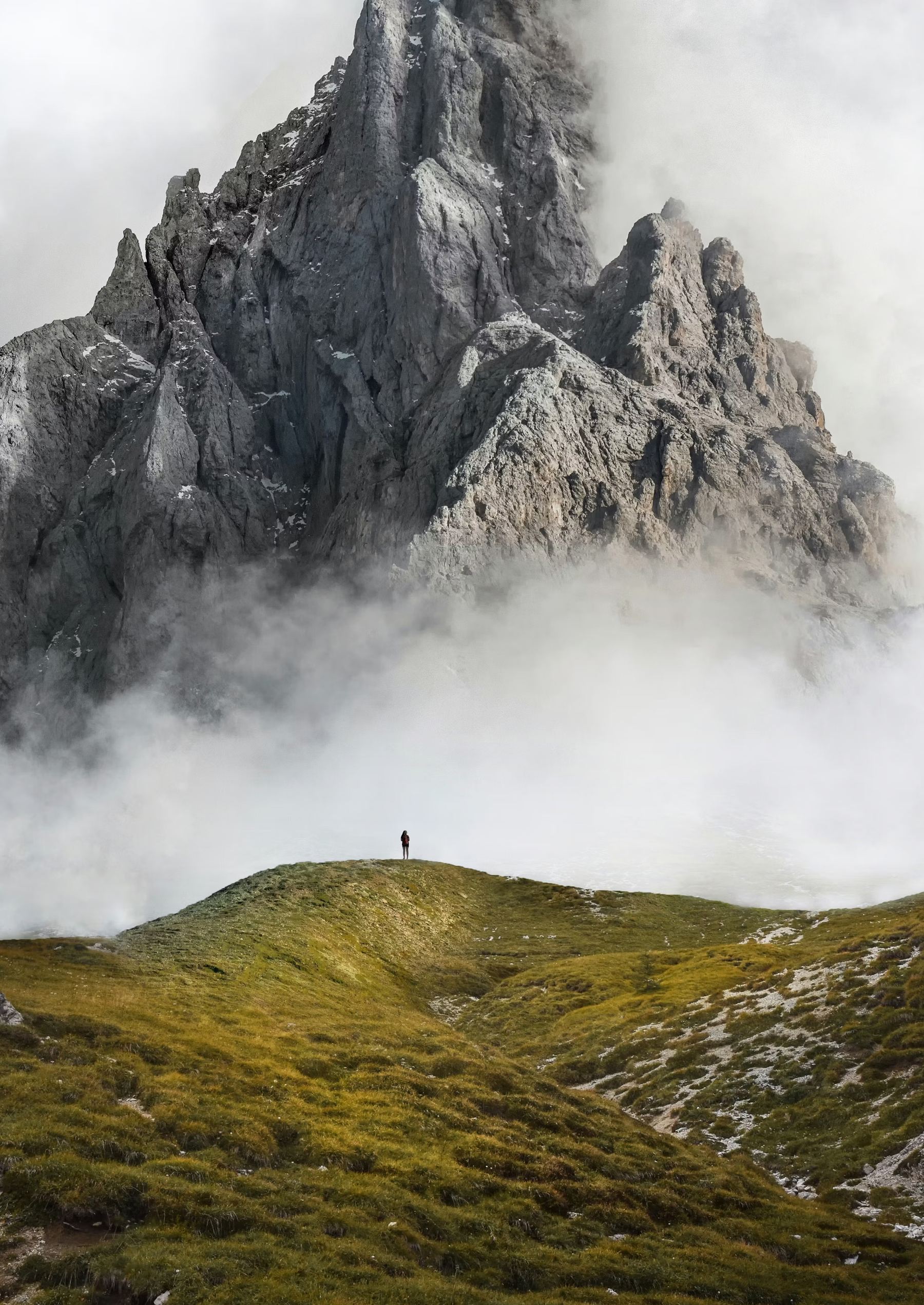 Silhouette on a ridge facing a peak in the mist